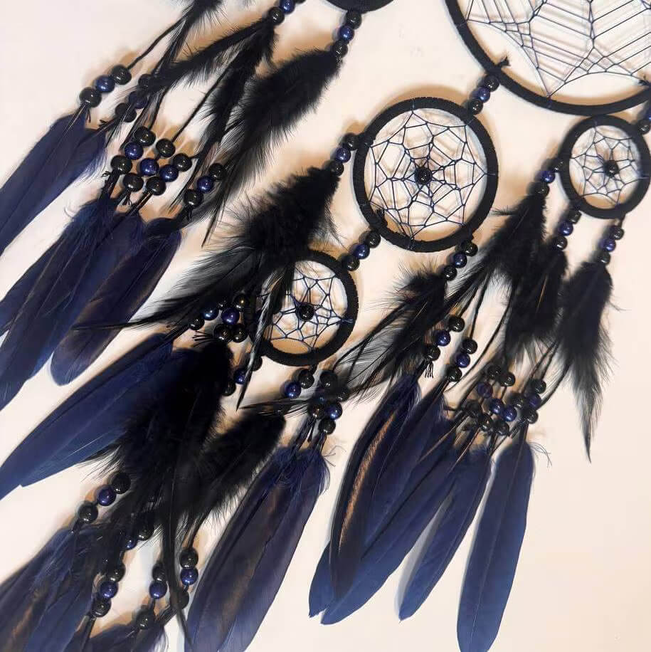 Dreamcatcher with black and blue feathers on a beige background