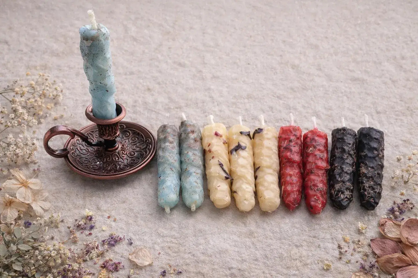 Colorful  natural beeswax candles arranged in a row on a textured surface with a candle holder.