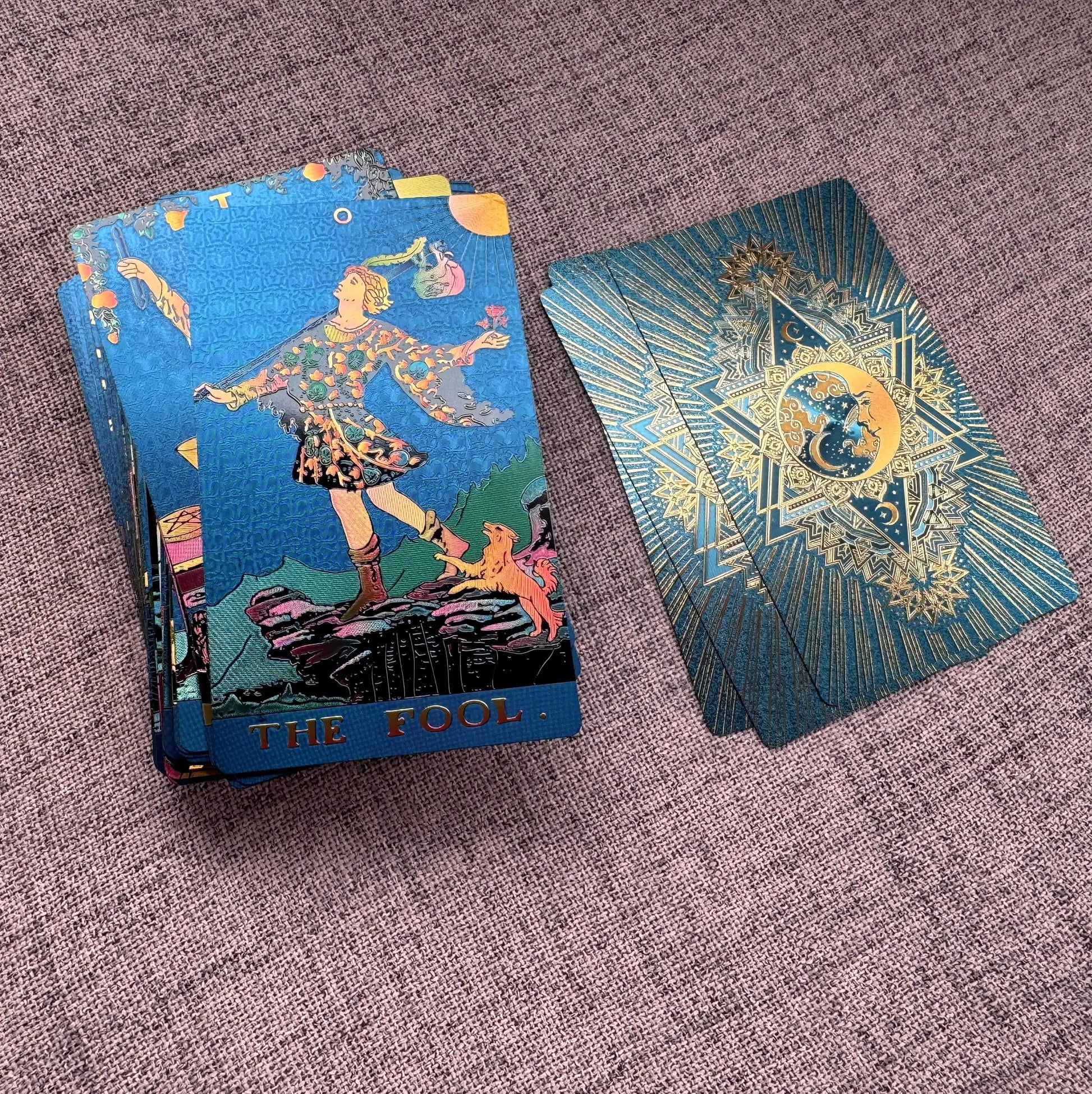 Two tarot cards on a textured surface, one open showing 'The Fool' card.