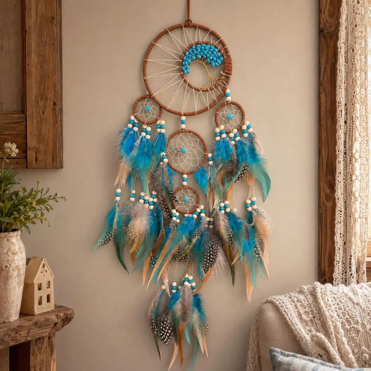 Decorative dreamcatcher with blue feathers hanging on a wall.
