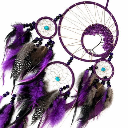 Purple dreamcatcher with feathers and beads on a white background
