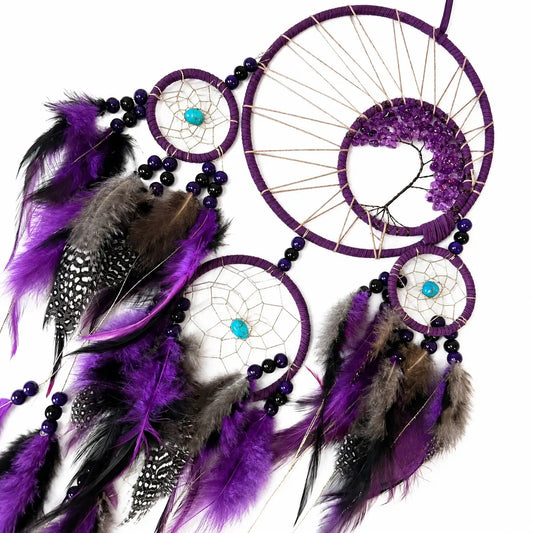 Purple dreamcatcher with feathers and beads on a white background