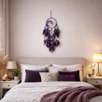 Decorative dreamcatcher on a wall above a bed with purple and white bedding.