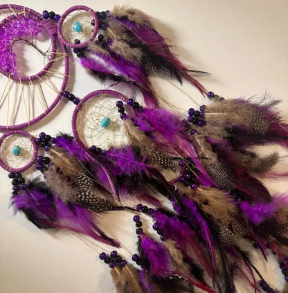 Purple dreamcatcher with feathers and beads on a light background