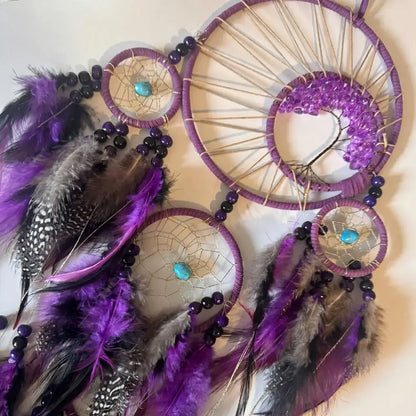 Dreamcatcher with purple feathers and beads on a beige background