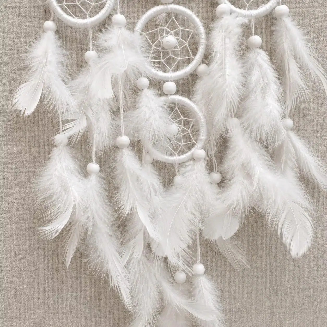 White dreamcatcher with feathers on a beige background