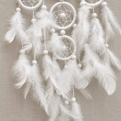 White dreamcatcher with feathers on a beige background