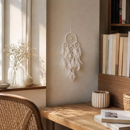 Decorative dreamcatcher hanging on a wall next to a wooden shelf with books and a vase.