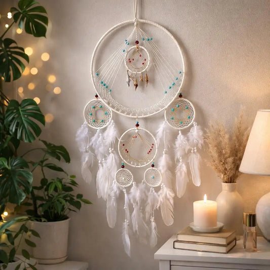 Decorative dreamcatcher hanging on a wall with a candle and books on a table in the background.