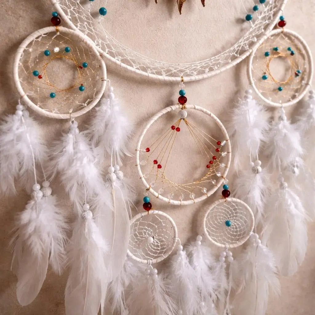 A set of four white dreamcatchers with feathers, beads, and gold webbing, arranged against a neutral beige background.