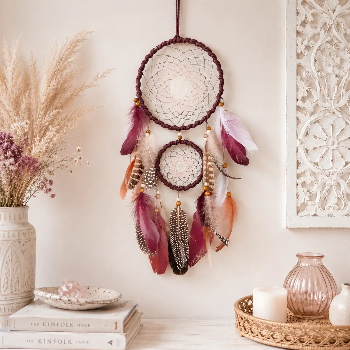 Decorative dreamcatcher with feathers hanging on a wall with decorative elements.