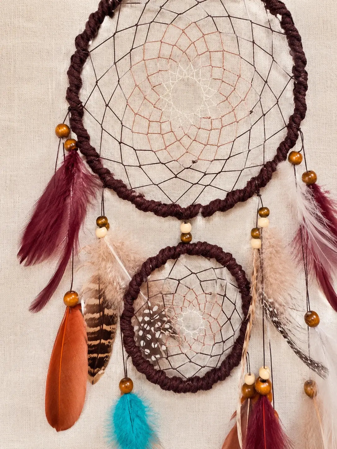 Dreamcatcher with feathers and beads on a beige background