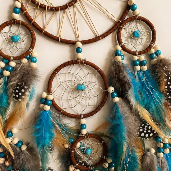 Dreamcatcher with blue and brown feathers on a white background